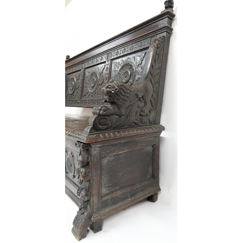 2001 - A 19TH CENTURY STAINED OAK GOTHIC STYLE SETTLE panel back carved with circular reliefs capped with t... 