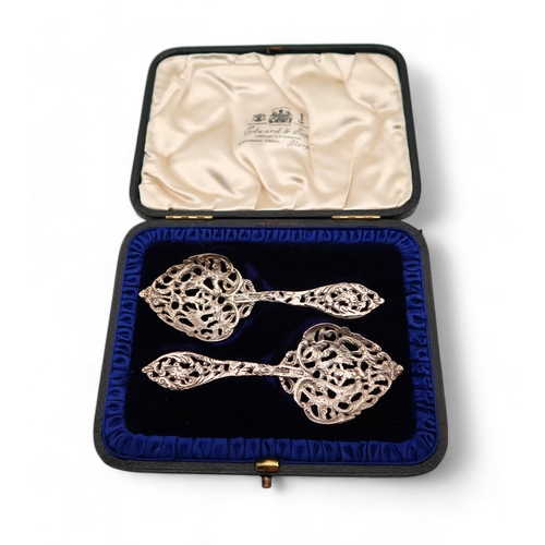 416 - A cased pair of ornate cast silver spoons, by John Millward Banks, Chester 1900, decorated with a ch... 