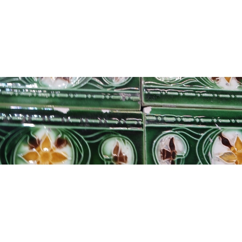 224 - A collection of half tiles, with tube line decoration of daffodils on a cream and green ground (76)