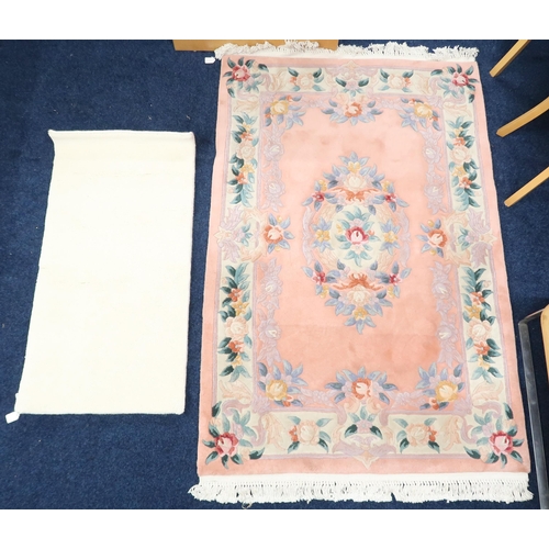 129 - A lot comprising a pink ground floral patterned Oriental style rug, 186cm long x 122cm wide and a sm... 