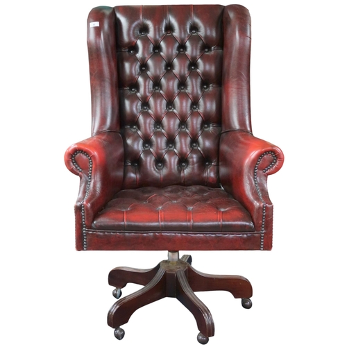 32 - A contemporary oxblood leather upholstered Chesterfield style wing back revolving desk chair, 126cm ... 