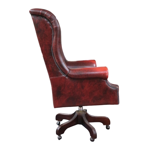 32 - A contemporary oxblood leather upholstered Chesterfield style wing back revolving desk chair, 126cm ... 