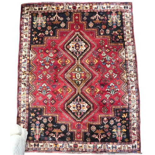 4 - A red ground Hamadan rug with multicoloured geometric diamond medallions and dark spandrels on a geo... 