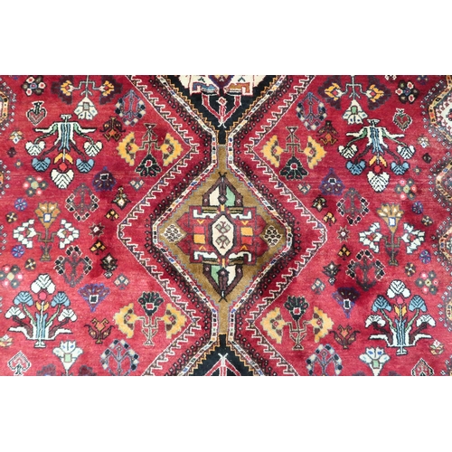 4 - A red ground Hamadan rug with multicoloured geometric diamond medallions and dark spandrels on a geo... 