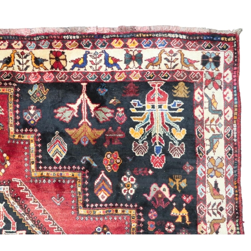 4 - A red ground Hamadan rug with multicoloured geometric diamond medallions and dark spandrels on a geo... 