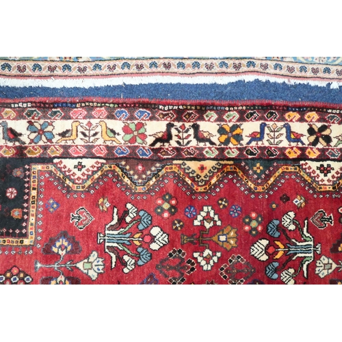 4 - A red ground Hamadan rug with multicoloured geometric diamond medallions and dark spandrels on a geo... 