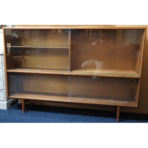 47 - A mid 20th century teak glazed bookcase with two pair of glazed sliding doors on shaped tapering sup... 