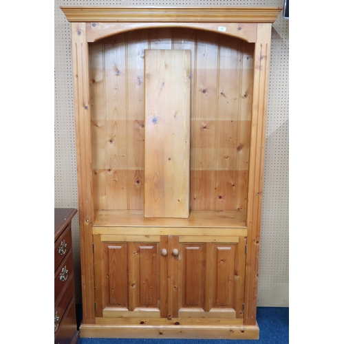 59 - A 20th century pine open bookcase with moulded cornice over three open shelves over pair of cabinet ... 