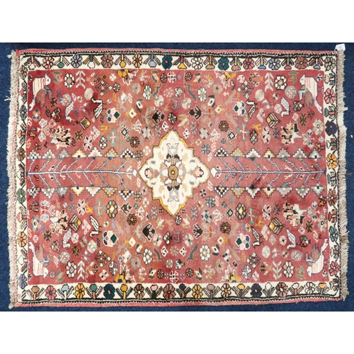 66 - A terracotta ground Persian style rug with cream central medallion on floral patterned ground within... 