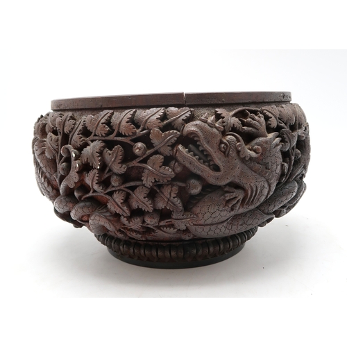 2423 - A BURMESE HEAVILY CARVED BOWL Decorated with dragons amongst dense foliage, 26cm diameter and lacque... 