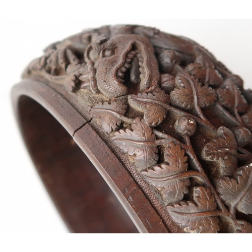 2423 - A BURMESE HEAVILY CARVED BOWL Decorated with dragons amongst dense foliage, 26cm diameter and lacque... 