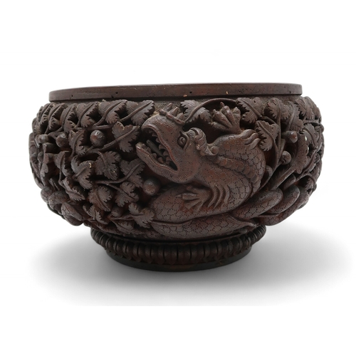 2423 - A BURMESE HEAVILY CARVED BOWL Decorated with dragons amongst dense foliage, 26cm diameter and lacque... 