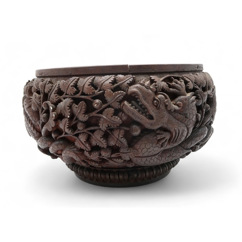 2423 - A BURMESE HEAVILY CARVED BOWL Decorated with dragons amongst dense foliage, 26cm diameter and lacque... 