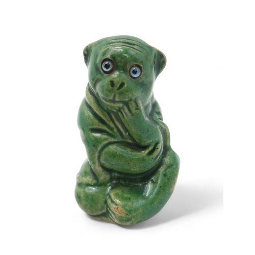 2230 - A DUNMORE POTTERY MODEL OF A MONKEYmodelled in seated position, green glazed with blue glass eyes, 6... 