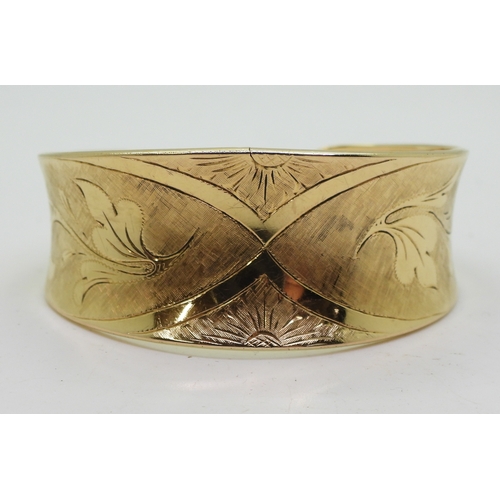 2722 - AN 18K GOLD BANGLEthe Italian made wide bangle has hand engraved floral detail throughout. Dimension... 