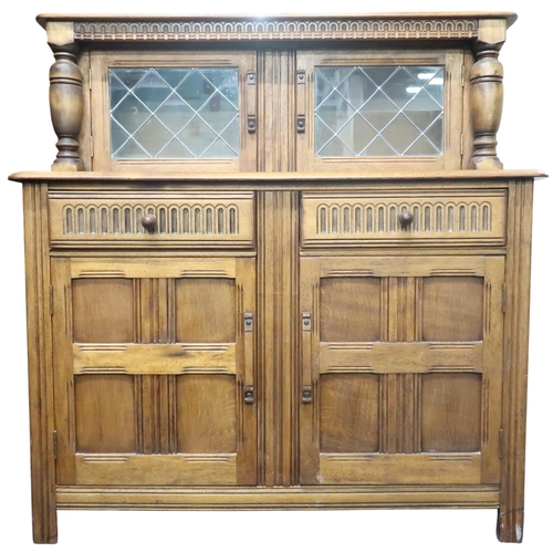 14 - A 20th century beech court cabinet with pair of leaded glass doors over two drawers over pair of pan... 