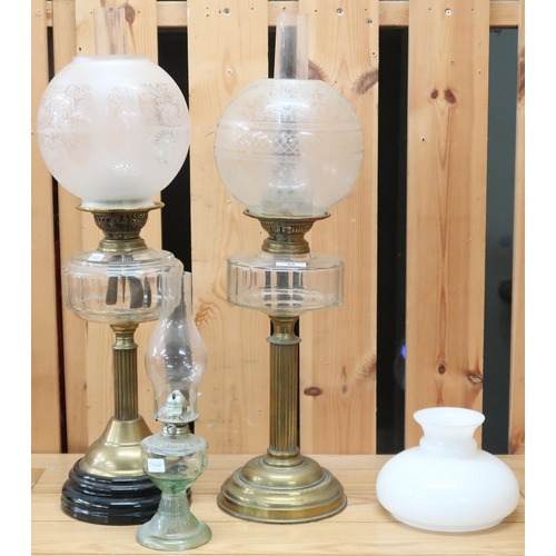 35 - A lot of two brass oil lamps with reeded column bases, a glass based oil lamp and a spare milk glass... 