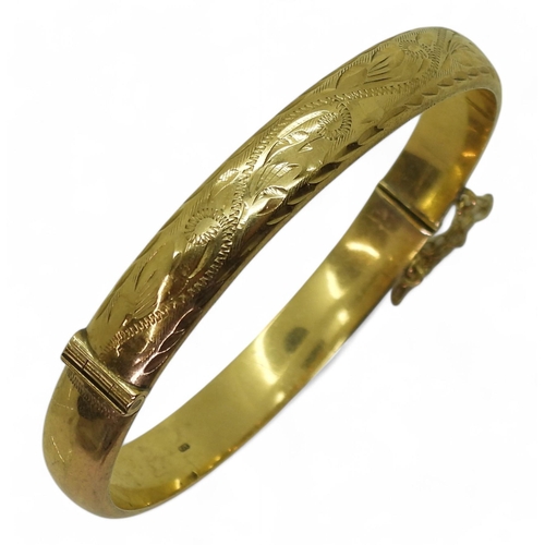 742 - A 9ct gold engraved bangle, inner dimensions 6cm x 5.5cm, weight 10.4gms