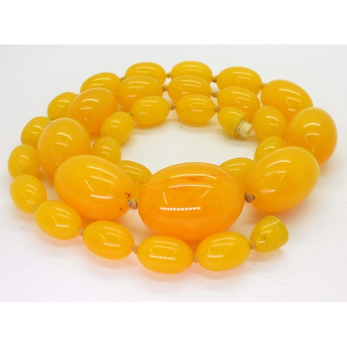 780 - A string of yellow amber coloured beads, the largest approx 3.5cm x 2.6cm, with overall fine crazing... 