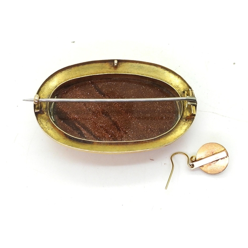 783 - A yellow metal mounted goldstone brooch, with engraved pattern to the edge, with one matching earrin... 