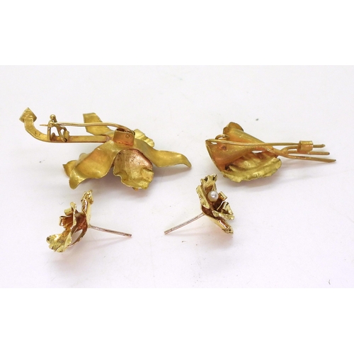 822 - An orchid brooch and earrings, and an arum lily brooch. Handmade, all stamped 18k, and set with fres... 