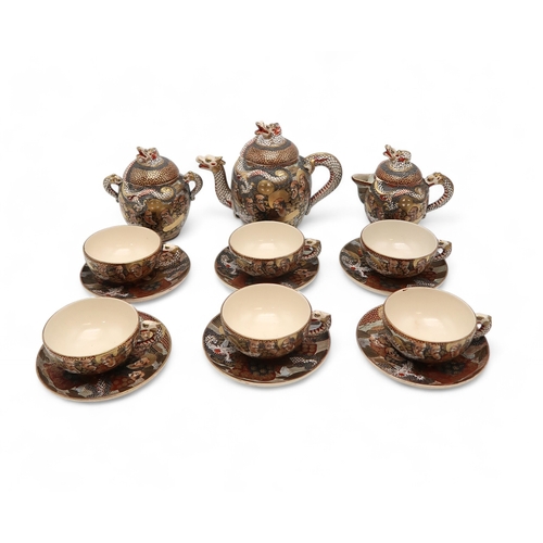 2437 - A SATSUMA TEA SERVICE Painted and moulded with dragons and Gods, comprising; teapot, sugar bowl, cre... 