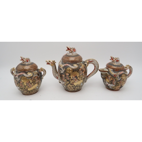 2437 - A SATSUMA TEA SERVICE Painted and moulded with dragons and Gods, comprising; teapot, sugar bowl, cre... 