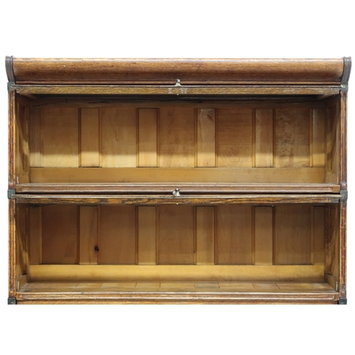 2026 - AN EARLY 20TH CENTURY OAK FOUR TIER SECTIONAL BOOKCASE with four glazed fall front slide back d... 