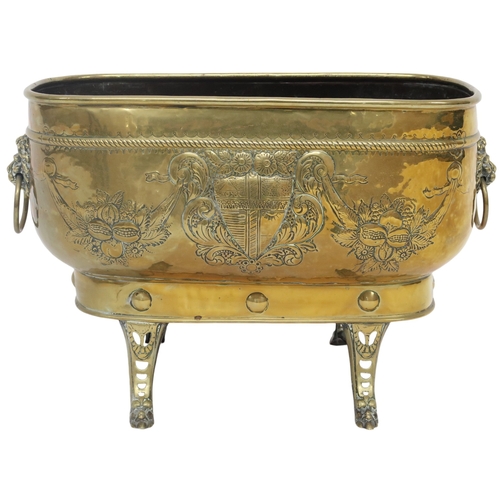 2037 - A VICTORIAN BRASS OBLONG PLANTER embossed with armorial shield and floral motifs with lion masq... 