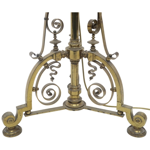 2054 - AN ARTS AND CRAFTS BRASS  TELESCOPIC STANDARD LAMP with tripod base decorated with scrolls and twist... 