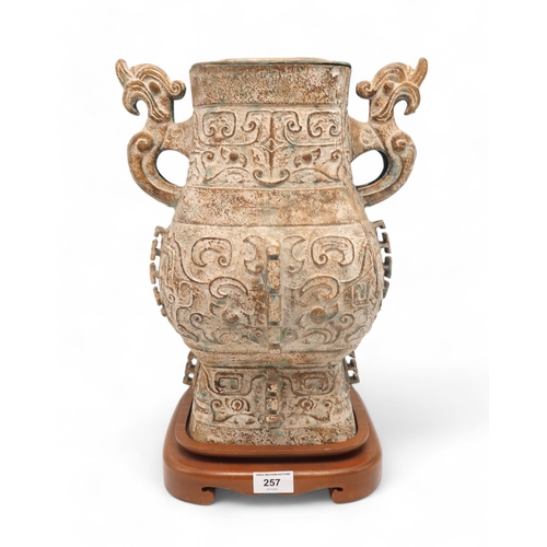 257 - An archaic style Chinese bronze vase with zoomorphic handles, on wooden base