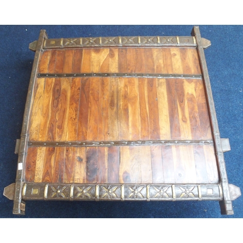 49 - A Indian hardwood coffee table converted from a bull cart with metal bound top and sides on carved s... 