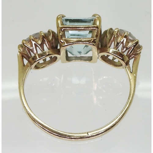 795 - A yellow metal ring set with a step cut aquamarine and round cut clear gems,finger size approx O, we... 