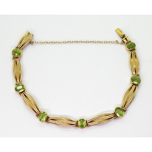 2774 - A 15CT GOLD PERIDOT BRACELETset with seven oval cut peridot of approx 6.5mm x 5mm, interspaced with ... 