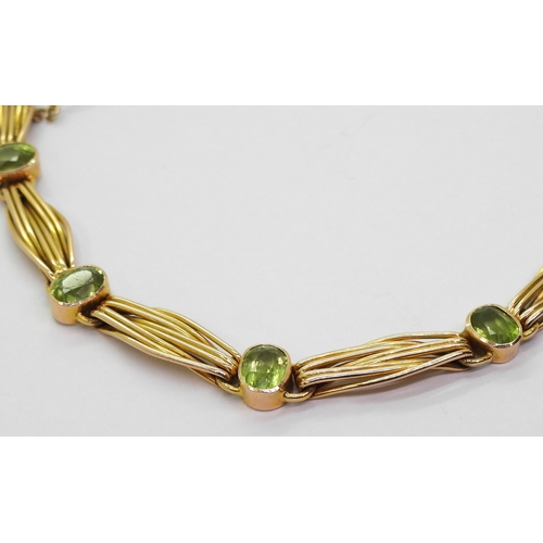 2774 - A 15CT GOLD PERIDOT BRACELETset with seven oval cut peridot of approx 6.5mm x 5mm, interspaced with ... 