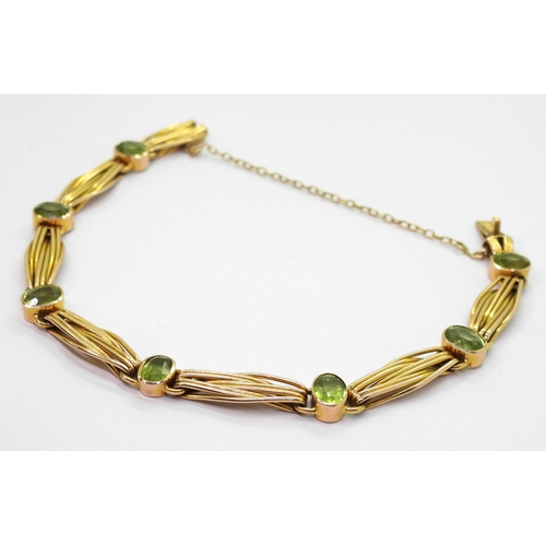 2774 - A 15CT GOLD PERIDOT BRACELETset with seven oval cut peridot of approx 6.5mm x 5mm, interspaced with ... 