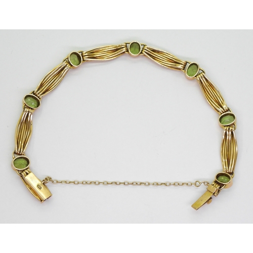 2774 - A 15CT GOLD PERIDOT BRACELETset with seven oval cut peridot of approx 6.5mm x 5mm, interspaced with ... 