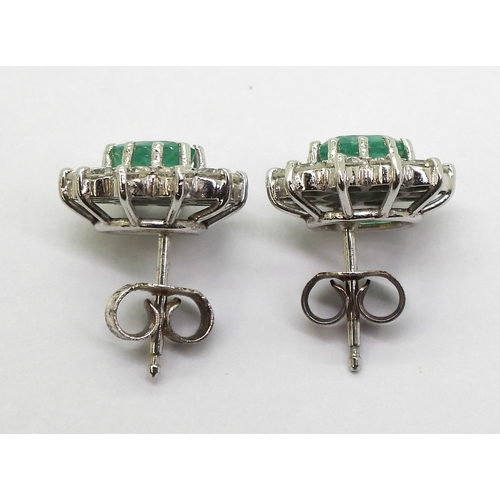 2794 - EMERALD AND DIAMOND EARRINGSin 18ct white gold mounts, the oval emeralds of approx 6mm x 5mm, surrou... 