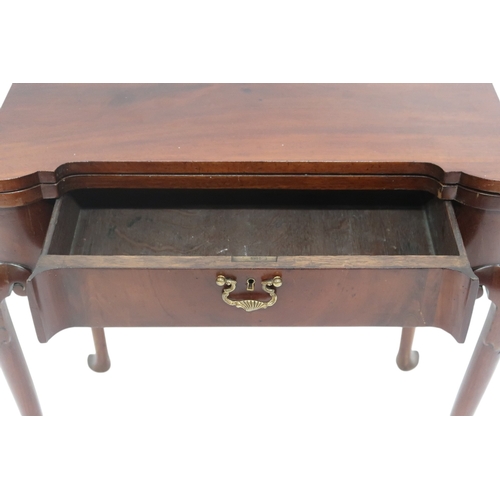 2063 - A GEORGE II WALNUT FOLDOVER CARD TABLE with shaped fold-over top concealing baize play surface ... 