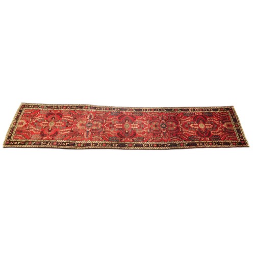 2162 - A RED GROUND IRANIAN KARAJEH RUNNERwith multicoloured geometric floral/foliate patterned ground with... 