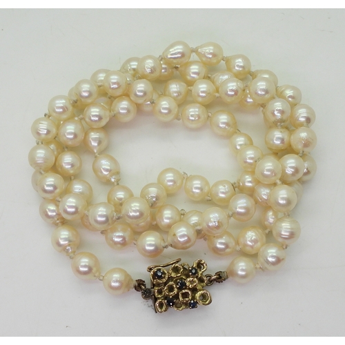 748 - A long string of baroque pearls with a retro yellow metal sapphire set box clasp, each pearl approx ... 