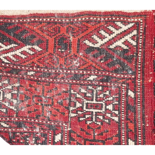 14 - A red ground Iranian wool Bokhara style rug with all-over lozenge design within geometric border, 14... 