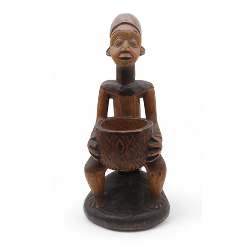 145 - A carved Nigerian figure, modelled holding a bowl, mid 20th century