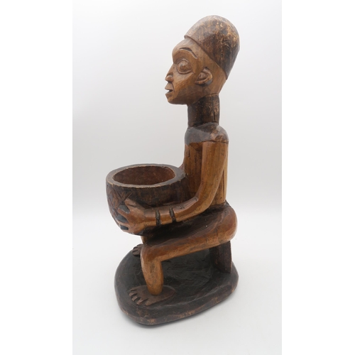 145 - A carved Nigerian figure, modelled holding a bowl, mid 20th century