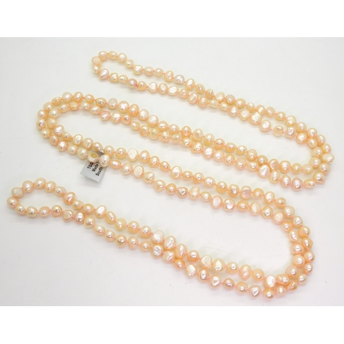 747 - A 152cm long, 'Endless string of peach baroque shaped cultured pearls, each pearl approx 5mm. With G... 