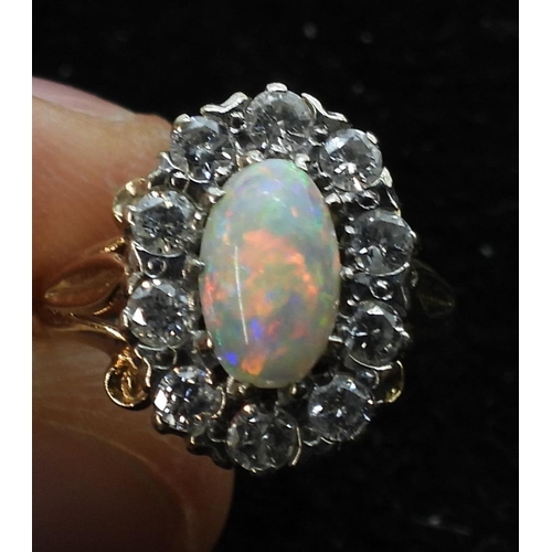 770 - An opal and diamond cluster ring, with fleur de lis shoulders, the shank is stamped K9. Size of the ... 