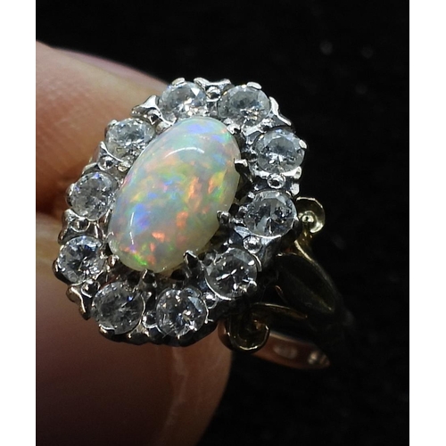 770 - An opal and diamond cluster ring, with fleur de lis shoulders, the shank is stamped K9. Size of the ... 