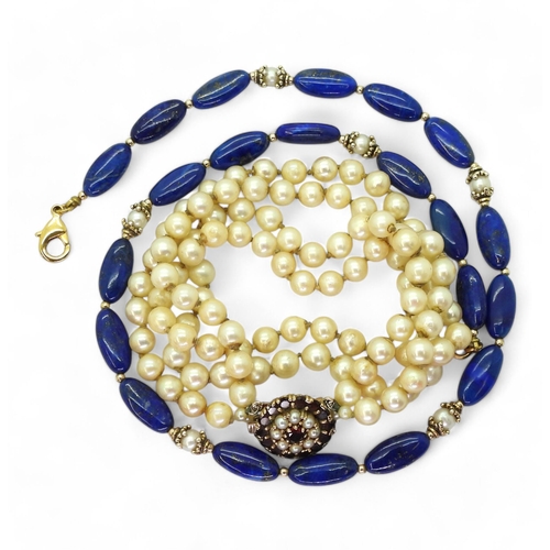 775 - A double string of pearls with a 9ct gold garnet and pearl clasp with a diameter of 18.2mm, length o... 