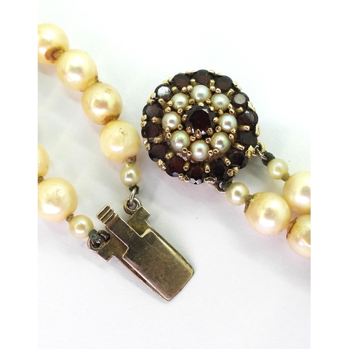 775 - A double string of pearls with a 9ct gold garnet and pearl clasp with a diameter of 18.2mm, length o... 