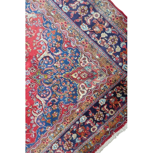 14 - A RED GROUND TABRIZ RUG with blue sunburst central medallion and blue spandrels on floral patterned ... 